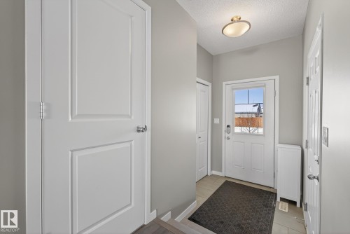 Inviting entryway featuring light gray walls, white paneled doors, and a front door with a window providing natural light - 8225 24 Avenue, Edmonton, AB - Indoor Photo Showing Other Room