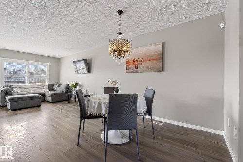 This bright living space features light gray walls, dark wood flooring, and a decorative chandelier - 8225 24 Avenue, Edmonton, AB - Indoor
