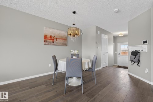 This living space features hardwood flooring, light grey walls, and a decorative chandelier - 8225 24 Avenue, Edmonton, AB - Indoor Photo Showing Dining Room