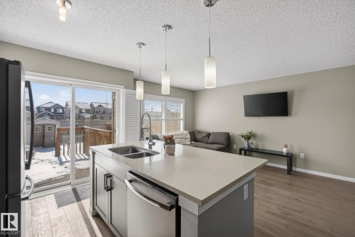The property features an open concept layout with an island kitchen, stainless steel appliances, and sliding glass doors leading to an exterior deck - 8225 24 Avenue, Edmonton, AB - Indoor Photo Showing Kitchen With Double Sink