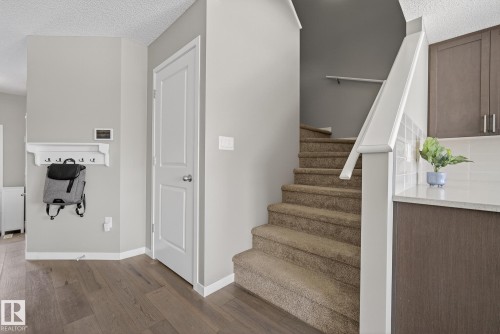 This entry area features hardwood floors and a carpeted staircase with a white railing - 8225 24 Avenue, Edmonton, AB - Indoor Photo Showing Other Room
