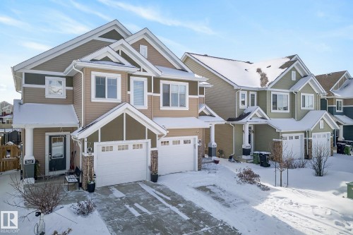 The property features a two-story exterior with light brown and dark brown siding, a peaked roof, and an attached garage with a white door - 8225 24 Avenue, Edmonton, AB - Outdoor With Facade
