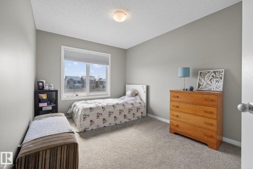 This room features neutral gray walls, light-colored carpeting, and a window providing views of the neighborhood - 8225 24 Avenue, Edmonton, AB - Indoor Photo Showing Bedroom