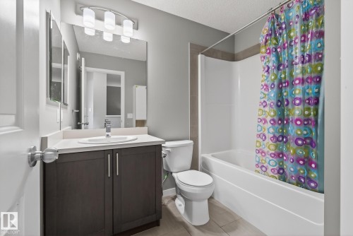 The bathroom features a vanity with a white countertop and an undermount sink, illuminated by an overhead light fixture - 8225 24 Avenue, Edmonton, AB - Indoor Photo Showing Bathroom