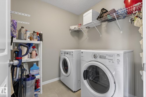 Laundry area with a front-loading washing machine, a dryer, and overhead wire shelving - 8225 24 Avenue, Edmonton, AB - Indoor Photo Showing Laundry Room