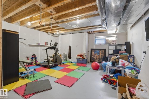 This versatile space features exposed ceiling joists and ductwork, with a window providing natural light - 8225 24 Avenue, Edmonton, AB - Indoor Photo Showing Basement