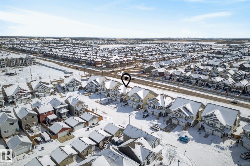 Aerial view of a residential neighbourhood with detached properties, townhouses, and apartment buildings, all featuring snow-covered rooftops, set against a clear sky - 8225 24 Avenue, Edmonton, AB - Outdoor With View