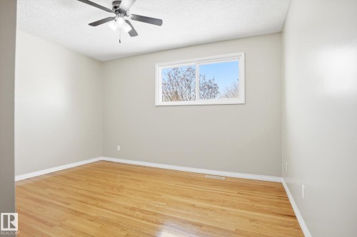 This room features hardwood floors, light-colored walls, a window with a view of trees and sky, and a ceiling fan with integrated lighting - 6 Garden Crescent, St. Albert, AB - Indoor Photo Showing Other Room