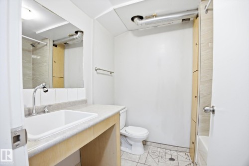 This bathroom features a vanity with an integrated sink and chrome faucet, a wall-mounted mirror, and a toilet - 6 Garden Crescent, St. Albert, AB - Indoor Photo Showing Bathroom
