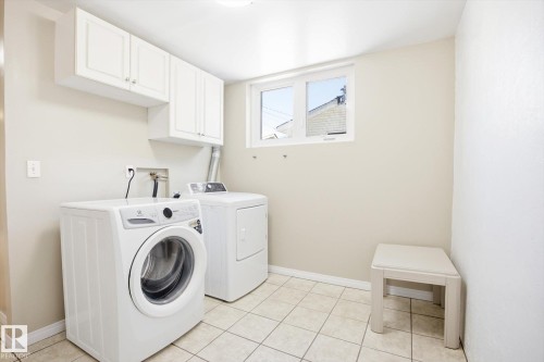 The property features a laundry area with white upper cabinets, a window, and tiled flooring - 6 Garden Crescent, St. Albert, AB - Indoor Photo Showing Laundry Room