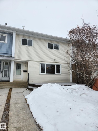 The property features light-colored horizontal siding, a front door with a window, and a concrete pathway leading to the entrance - 6 Garden Crescent, St. Albert, AB - Outdoor