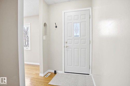 Entryway featuring a white paneled door with a decorative glass insert, a recessed wall niche, and hardwood floors visible in the adjoining area - 6 Garden Crescent, St. Albert, AB - Indoor Photo Showing Other Room