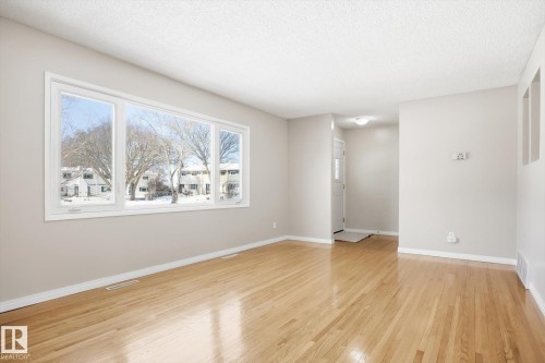 The property features hardwood flooring throughout, a large window providing ample natural light, and a clean, neutral color palette on the walls and trim - 6 Garden Crescent, St. Albert, AB - Indoor Photo Showing Other Room