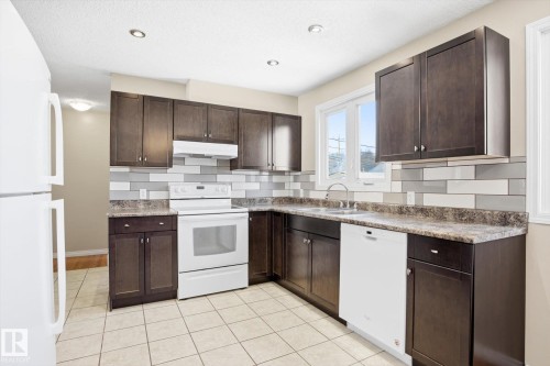 Kitchen featuring dark wood cabinetry, white appliances, a tiled backsplash, and recessed lighting - 6 Garden Crescent, St. Albert, AB - Indoor Photo Showing Kitchen With Double Sink