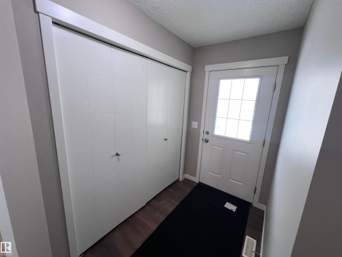The entryway features a white front door with a window, dark wood flooring, and a spacious closet with white bifold doors - 1421 26 Avenue, Edmonton, AB - Indoor Photo Showing Other Room