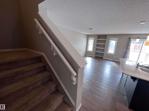 The property features a staircase with carpeted treads and a handrail, leading to a main living area with dark wood flooring - 1421 26 Avenue, Edmonton, AB - Indoor Photo Showing Other Room