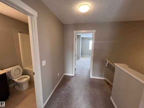 The property features neutral-toned walls, carpeted flooring, and white trim throughout the hallway and into a visible room - 1421 26 Avenue, Edmonton, AB - Indoor Photo Showing Other Room