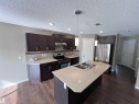 The kitchen features dark wood cabinetry, a light-colored island with an integrated double sink, stainless steel appliances, and pendant lighting - 1421 26 Avenue, Edmonton, AB  - Indoor Photo Showing Kitchen With Stainless Steel Kitchen With Double Sink With Upgraded Kitchen 