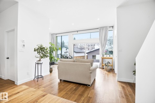 Living room featuring hardwood floors, large windows providing natural light, and sliding glass doors - 9821 85 Avenue, Edmonton, AB - Indoor Photo Showing Living Room