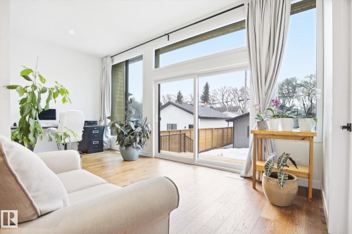 Living area featuring hardwood flooring and expansive windows providing natural light - 9821 85 Avenue, Edmonton, AB - Indoor