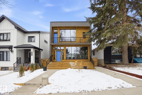 The property features a contemporary architectural style with wood-toned siding and large windows - 9821 85 Avenue, Edmonton, AB - Outdoor With Facade