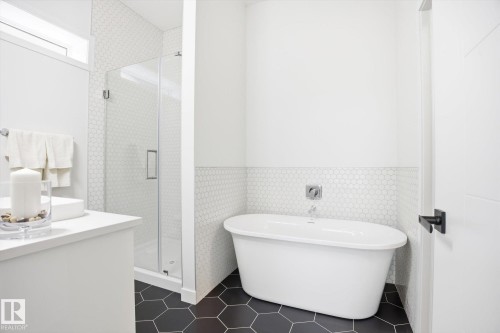 This bathroom features a freestanding bathtub, a glass-enclosed shower, and a vanity with a white countertop - 9821 85 Avenue, Edmonton, AB - Indoor Photo Showing Bathroom
