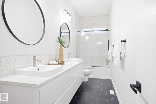 Modern bathroom featuring a double vanity with vessel sinks, black framed mirrors, and hexagonal floor tiles - 9821 85 Avenue, Edmonton, AB - Indoor Photo Showing Bathroom