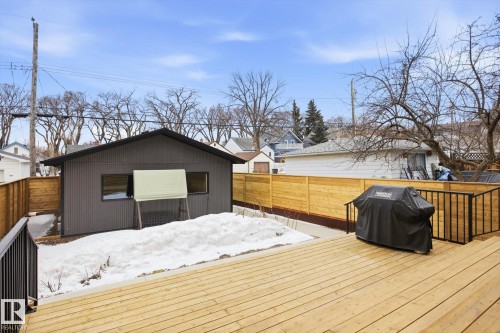 The property features a spacious wooden deck with black railings - 9821 85 Avenue, Edmonton, AB - Outdoor With Deck Patio Veranda With Exterior