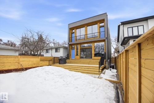 The property features a multi-level wooden deck with black railings, leading to a spacious yard - 9821 85 Avenue, Edmonton, AB - Outdoor