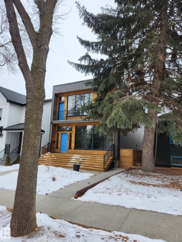 The property features a contemporary architectural style with wood siding and large windows - 9821 85 Avenue, Edmonton, AB - Outdoor With Deck Patio Veranda