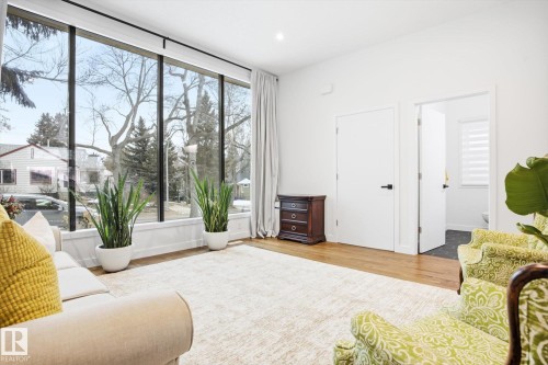 The living area features expansive floor-to-ceiling windows, offering abundant natural light and exterior views - 9821 85 Avenue, Edmonton, AB - Indoor