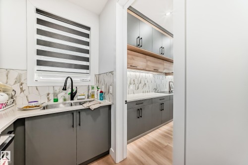 Well-appointed kitchen featuring a window with horizontal blinds, a stainless steel sink with a matte black faucet, and grey cabinetry - 15108 11 Street, Edmonton, AB - Indoor