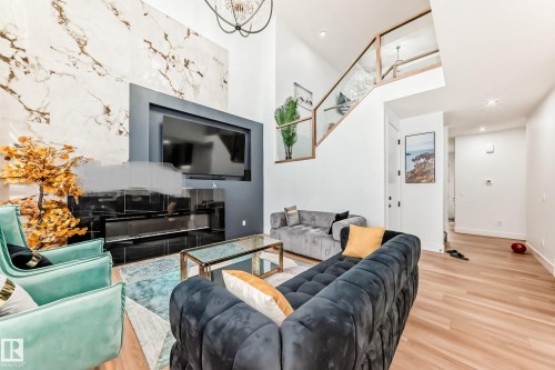 The living area features high ceilings, hardwood flooring, and a stairway with glass paneling - 15108 11 Street, Edmonton, AB - Indoor