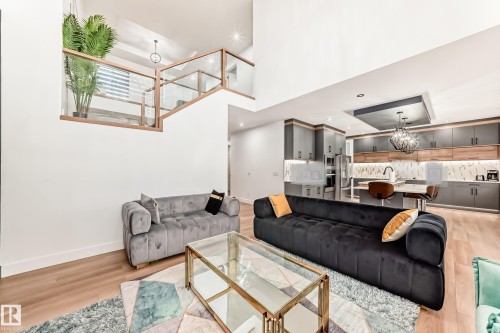Open-concept living area featuring hardwood flooring, a glass and wood railing, and a modern kitchen with grey and wood cabinetry - 15108 11 Street, Edmonton, AB - Indoor
