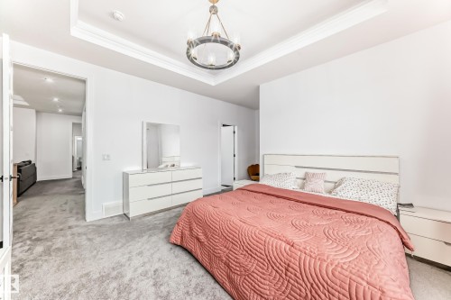 This room features a high tray ceiling with crown molding and a prominent chandelier - 15108 11 Street, Edmonton, AB - Indoor Photo Showing Bedroom