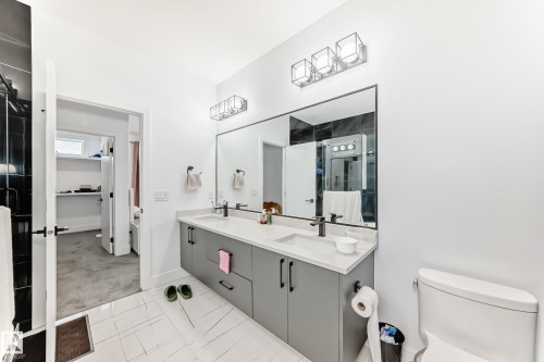 The bathroom features a double vanity with grey cabinetry, a large mirror, and modern light fixtures - 15108 11 Street, Edmonton, AB - Indoor Photo Showing Bathroom