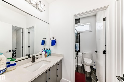 Well-appointed bathroom featuring a vanity with a rectangular sink, a dark colored faucet, and a large mirror - 15108 11 Street, Edmonton, AB - Indoor Photo Showing Bathroom