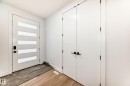 The property features light-toned wood flooring, a white front door with horizontal frosted glass panels, and a white double door with black hardware - 15108 11 Street, Edmonton, AB  - Indoor Photo Showing Other Room 