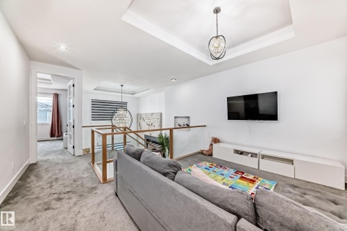 The property features a bright living area with a tray ceiling and a modern pendant light fixture - 15108 11 Street, Edmonton, AB - Indoor