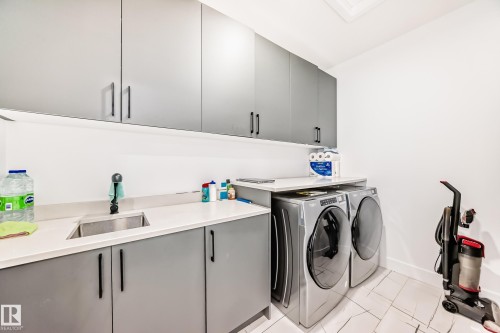 The laundry area features grey cabinetry, a stainless steel sink, and white countertops, providing a functional space - 15108 11 Street, Edmonton, AB - Indoor Photo Showing Laundry Room