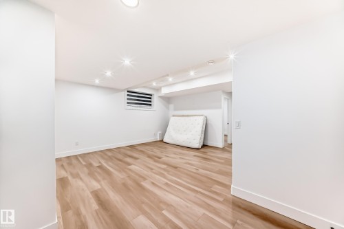 This spacious room features light-toned wood flooring, recessed lighting, and white walls with white baseboards - 15108 11 Street, Edmonton, AB - Indoor