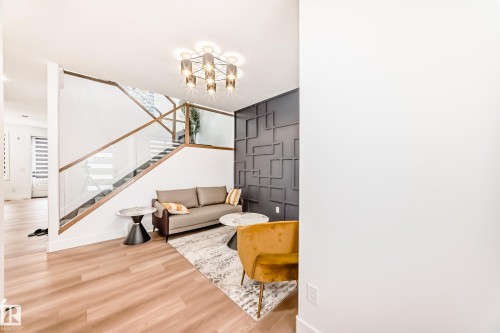 The property features a modern staircase with glass railings and wood accents, alongside a room with light wood flooring - 15108 11 Street, Edmonton, AB - Indoor Photo Showing Other Room