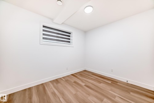 This room features light wood-look flooring, bright white walls, and a window with horizontal blinds - 15108 11 Street, Edmonton, AB - Indoor Photo Showing Other Room