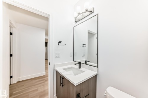 Bathroom featuring a vanity with a white countertop, an undermount sink, and a black faucet - 15108 11 Street, Edmonton, AB - Indoor Photo Showing Bathroom