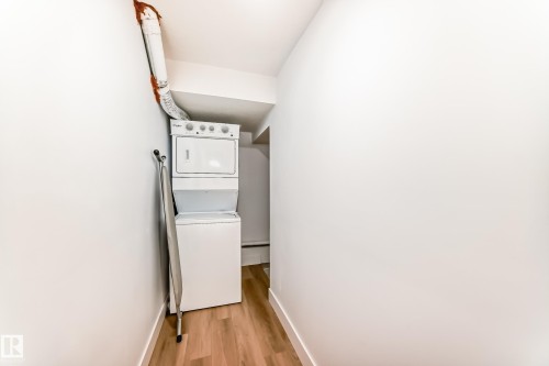 Laundry area featuring a stacked washer and dryer unit, and hardwood flooring - 15108 11 Street, Edmonton, AB - Indoor Photo Showing Laundry Room