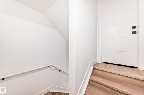 The property features light wood stairs and a white door with black hardware, complementing the bright white walls and trim - 15108 11 Street, Edmonton, AB - Indoor Photo Showing Other Room