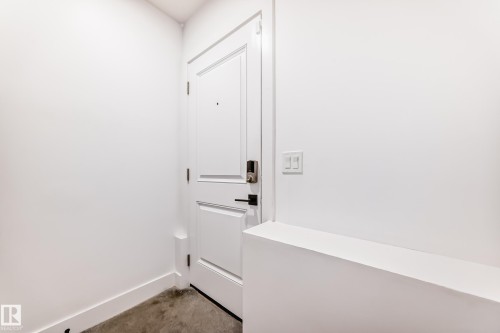 Entryway with a white paneled door featuring a smart lock and a dark handle - 15108 11 Street, Edmonton, AB - Indoor Photo Showing Other Room