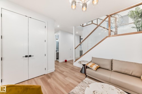 Living area featuring light wood flooring, white walls, and a modern staircase with a glass and wood railing - 15108 11 Street, Edmonton, AB - Indoor