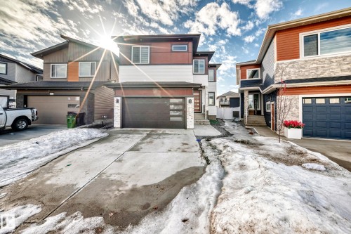 The property features a modern exterior design with a combination of white siding, dark brown accents, and red paneling - 15108 11 Street, Edmonton, AB - Outdoor With Facade