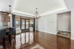 Living area featuring hardwood floors, a tray ceiling with recessed lighting, and a chandelier - 
